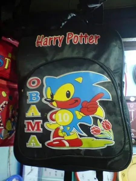 A shanzhai children's backpack photographed in a Chinese market, combining the words 'Harry Potter' and 'OBAMA' with an off-model Sonic the Hedgehog character.